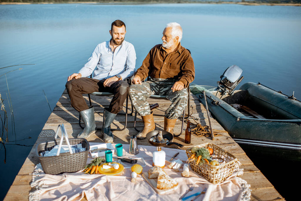 Grand-père avec fils adulte sur le pique-nique sur le lac
 - Photo, image