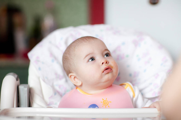 6ヶ月のアジア系の赤ん坊を椅子に乗せて。お母さんは娘に食べ物をブレンドして - 写真・画像