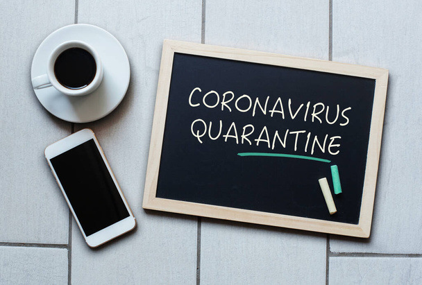 Coronavirus Quarantine text written on blackboard. COVID-19 - Wuhan Novel Coronavirus pneumonia. Chalk board with coffee and mobile phone. - Foto, imagen