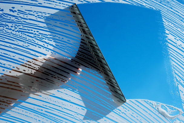 Καθαρισμός σαπουνόφουσκες παράθυρα με squeegee κατά ηλιόλουστο μπλε ουρανό. Ανοιξιάτικο σπίτι έννοια καθαρισμού. Αντιγραφή χώρου - Φωτογραφία, εικόνα