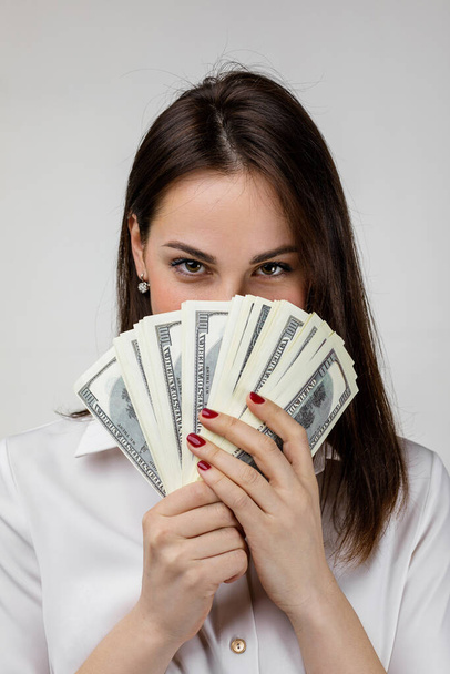 woman in white shirt hiding behind bunch of money banknotes - Foto, Imagen