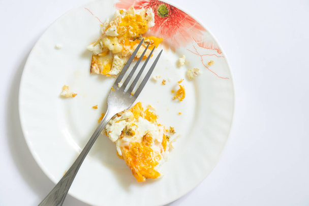 τηγανητό αυγό σε πιάτα με ένα πιρούνι περισσέψει φαγητό σε ένα απομονωμένο φόντο - Φωτογραφία, εικόνα