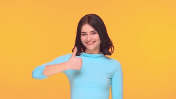 Studio portrait of young and expressive teenage brunette girl over yellow background. - Video, Çekim