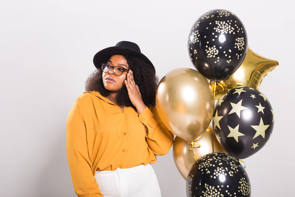 Vacanze, festa e divertimento - Ritratto di giovane donna afro-americana sorridente in cerca di stile su sfondo bianco con palloncini
. - Foto, immagini