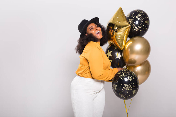 Holidays, party and fun concept - Portrait of smiling young African-American young woman looking stylish on white background holding balloons. - Foto, Imagen