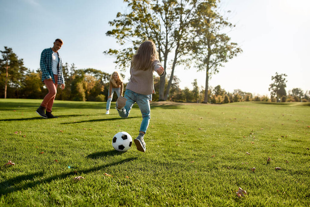 Reúne a la familia. Familia feliz jugando con una pelota en el prado
 - Foto, Imagen