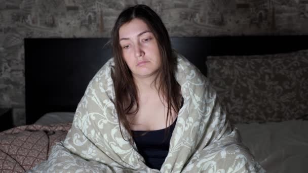 brünette Frau sitzt mit traurigem Blick am Bettrand und gähnt - Filmmaterial, Video