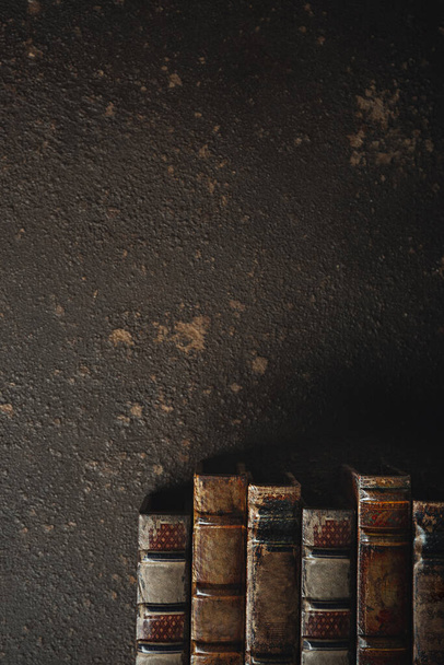 Vanhanaikainen tasainen makasi pino antiikki nahka sidottu kirjoja tummaa taustaa vasten
 - Valokuva, kuva