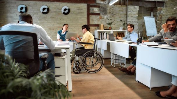 Gemeinsam erreichen wir mehr. Mann im Rollstuhl arbeitet im Büro - Foto, Bild