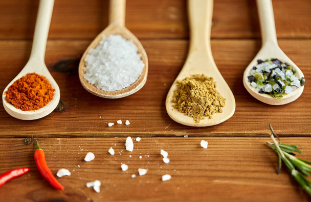 Löffel mit Gewürzen und Salz auf Holztisch - Foto, Bild