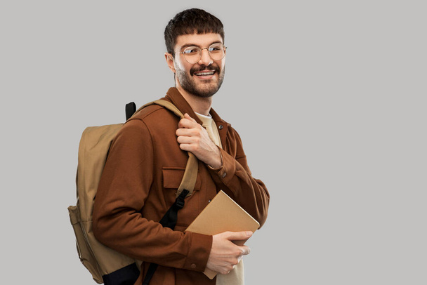 χαμογελαστός νεαρός άνδρας με σακίδιο και ημερολόγιο - Φωτογραφία, εικόνα