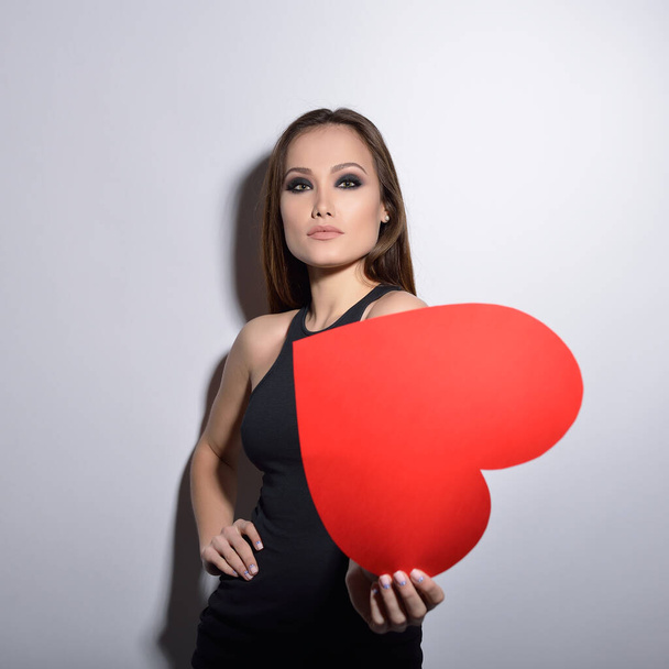 Heartbreaker. Temptress. Seductive woman. Portrait of amazing young fashion woman posing at studio with red heart. Love. Valentine's day.  - Φωτογραφία, εικόνα