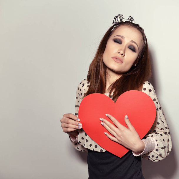 Heartbreaker. Temptress. Seductive woman. Portrait of funny pinup young fashion woman posing at studio with red heart. Love. Valentine's day, image toned. - Fotoğraf, Görsel