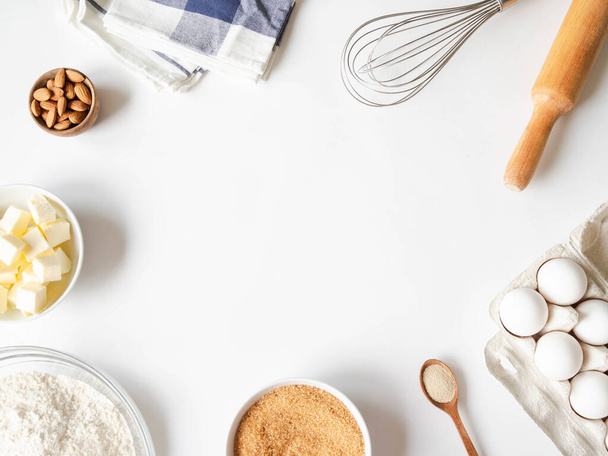 Keret különböző sütőipari összetevők - liszt, tojás, cukor, vaj, száraz élesztő, dió és konyhai eszközök fehér alapon. Első látásra. Fénymásolási hely - Fotó, kép
