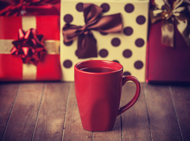 Cup of coffee and gifts at background - Foto, Imagen
