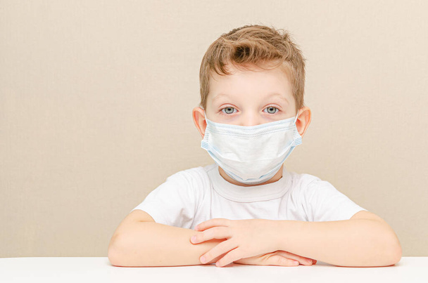 Roztomilý čtyřletý chlapec v lékařské masce. Děti v karanténě kvůli epidemii. Dítě sedí doma smutné a osamělé - Fotografie, Obrázek