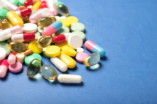 Pills and capsules on a blue background.Concept of medicine and health. - 写真・画像