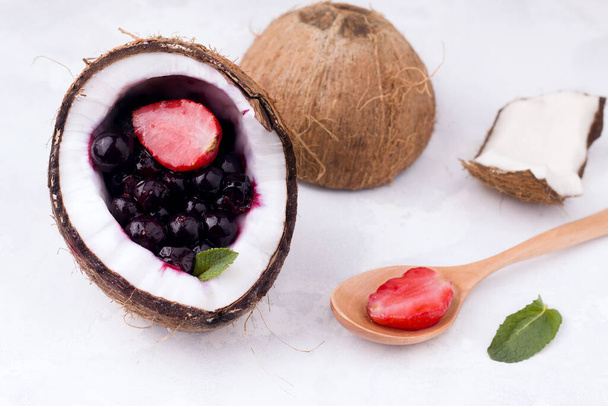 berries of strawberries and currants in a half of coconut on a white background. summer concept - Foto, immagini
