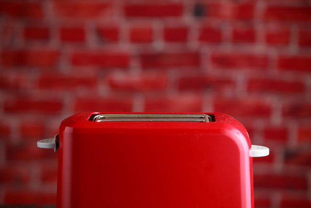 tostadora roja sobre fondo de pared de ladrillos. Equipo de cocina - Foto, imagen