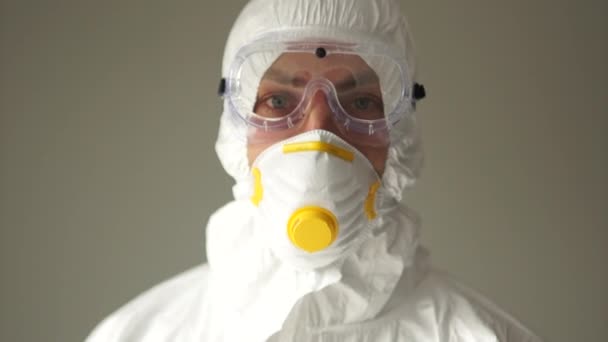 Nahes Porträt eines Mannes in Schutzanzug und blauen Handschuhen zeigt eine Daumen-hoch-Geste, schlechte Nachrichten, die Ausbreitung des Coronavirus, eine aggressive Geste - Filmmaterial, Video