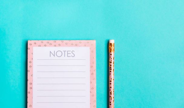 Różowy Notatnik i śliczne złote ołówki na modne zielone tło. Płaski styl minimalizmu. - Zdjęcie, obraz