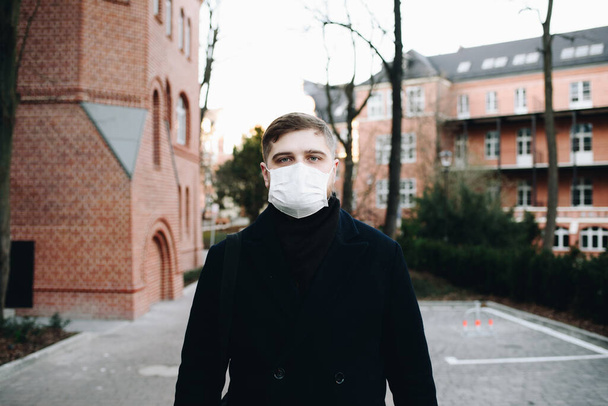 Kaukasischer junger Mann läuft draußen mit chirurgischer Gesichtsmaske, um sich vor dem Coronavirus covid-19 covid 19 Virus zu schützen - Foto, Bild