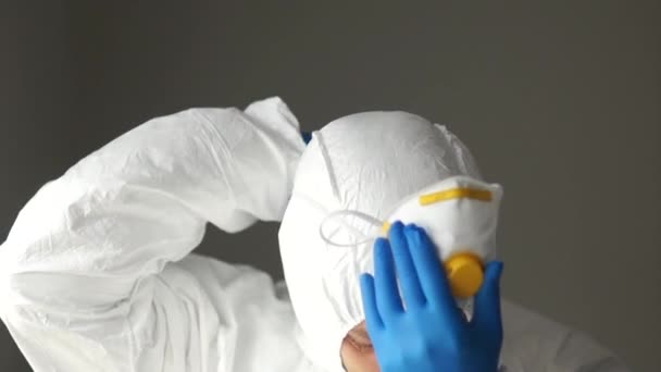 Close portrait of a man in a protective suit wears a mask respirator. Medical professionals threatening the spread of coronavirus - Imágenes, Vídeo