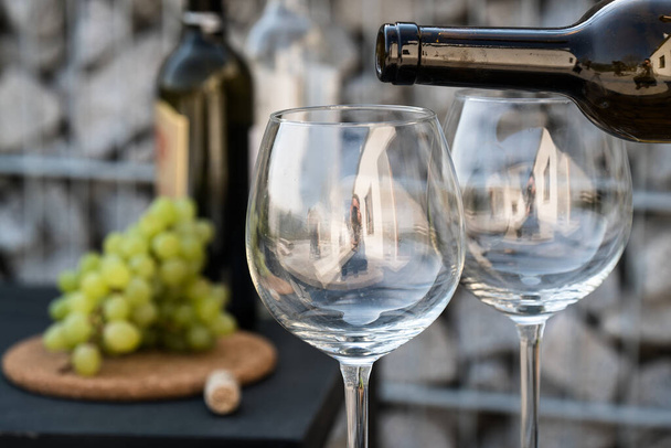 nalévání bílého vína do sklenic, s hrozny na pozadí - Fotografie, Obrázek