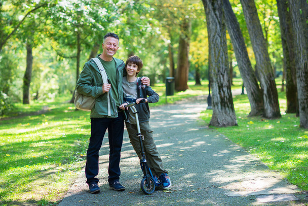 Babasının oğluyla birlikte sonbahar parkında yürüdüğü portre. Aile eğlencesi. Ebeveynlik. Ebeveynlik, görüntü tonu ve gürültü eklendi. - Fotoğraf, Görsel