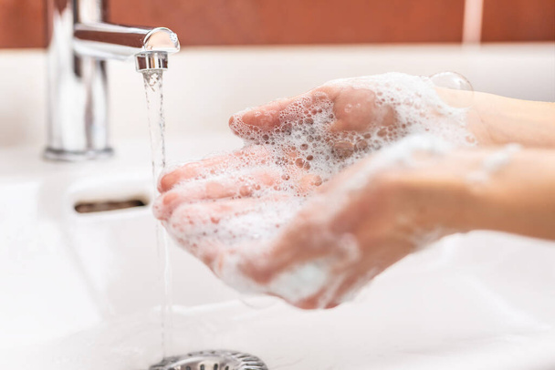 Мытье рук с водой и жидким мылом в ванной комнате. Антивирусная концепция гигиены
 - Фото, изображение