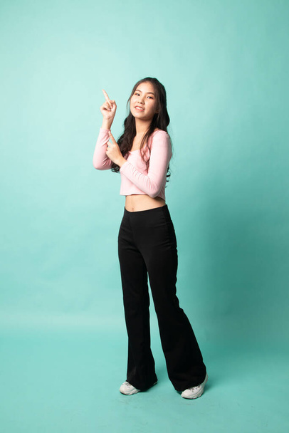 Full body of beautiful young asian woman pointing up on cyan background - Foto, Bild