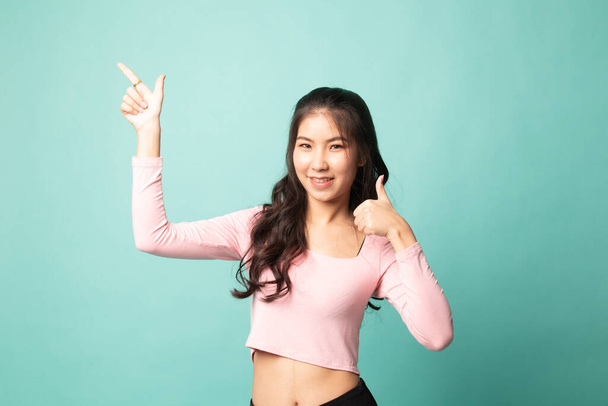 Young Asian woman point and thumbs up on cyan background - Foto, immagini