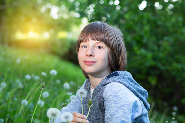 Çocuk mavi yeşil çimlerin üzerine karahindiba üflüyor, yaz doğası. Çocukluk, rüya, yaz, iyi bir ruh hali.. - Fotoğraf, Görsel