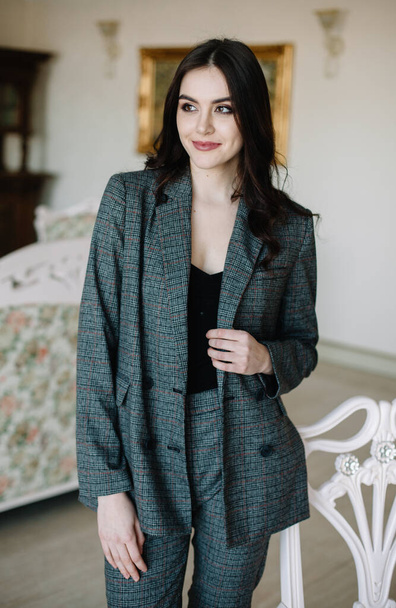 Young beautiful fashion model woman in a gray strict vintage suit sits on office - Фото, зображення