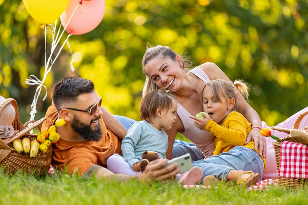 Joyful family picnicking in the park.Family picnicking together.Family on picnic at sunny day.Leisure, holidays, people and love concept. - 写真・画像