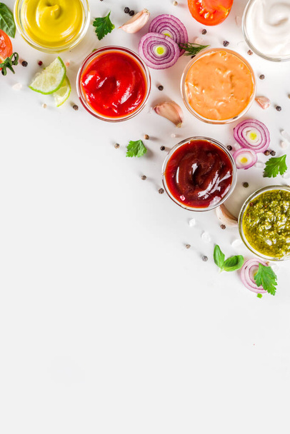 Set of sauces in small bowls - ketchup, mayonnaise, mustard, bbq sauce, pesto, classic burger sauce, with spices and herbs in. White background copy space top view - Photo, Image