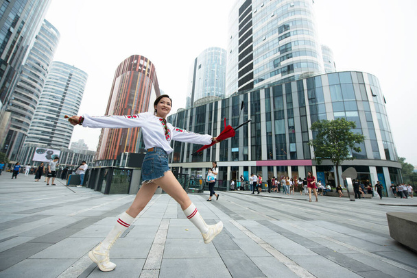 Красивая улыбающаяся китайская молодая женщина в традиционной украинской одежде позирует в центре Пекина, Китай. - Фото, изображение