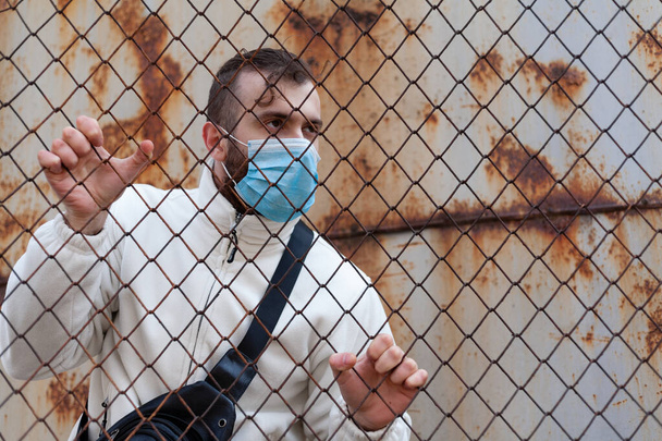 De man met het antivirale masker is in het verboden gebied. Het concept van quarantaine en overtreding van de wet. - Foto, afbeelding