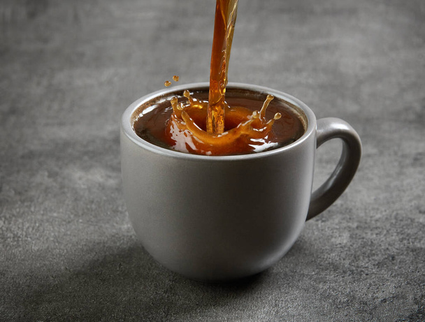 кава вливається в чашку на сірому фоні
 - Фото, зображення