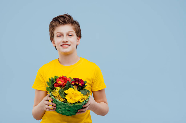 handsome preteen boy with basket of flowers in his hand, - 写真・画像