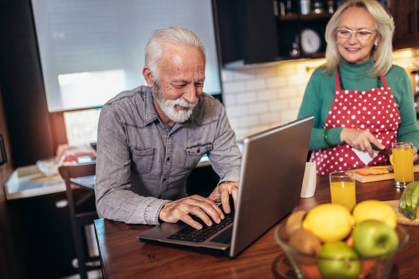 Feliz casal aposentado navegando na internet juntos em um computador portátil.Quarentena. Conceito de saúde
. - Foto, Imagem