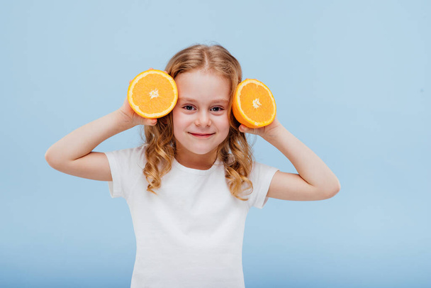 little happy girl with an orange in her hand, - Fotografie, Obrázek