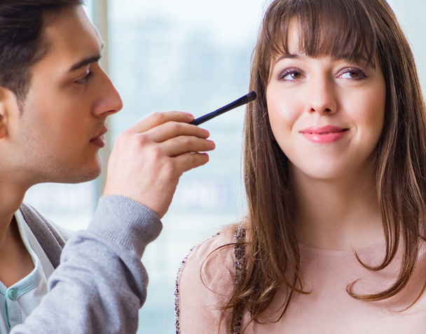 Άντρας κάνει make-up για χαριτωμένο γυναίκα στο σαλόνι ομορφιάς - Φωτογραφία, εικόνα