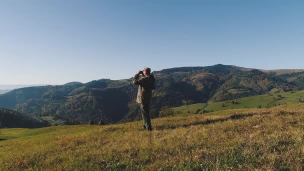 The hunter raised his binoculars, looking for his next destination in the mountains - Materiaali, video