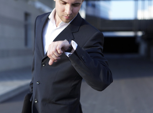 A handsome business man looking at watch - 写真・画像