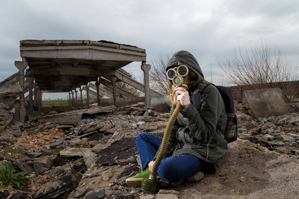 Human in gas mask among ruins and dramatic sky background. Enviromental pollution, ecology disaster, radiation, biological hazard concept. - Photo, Image