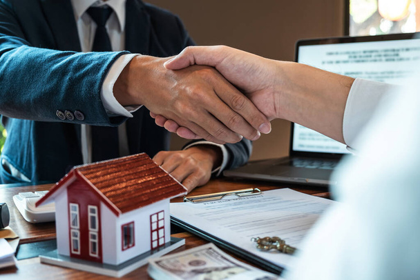 Agent nieruchomości ściskają ręce po dobrej cenie i daje dom, klucze do klienta po podpisaniu umowy na zakup domu z zatwierdzonym formularzem wniosku o nieruchomość. - Zdjęcie, obraz