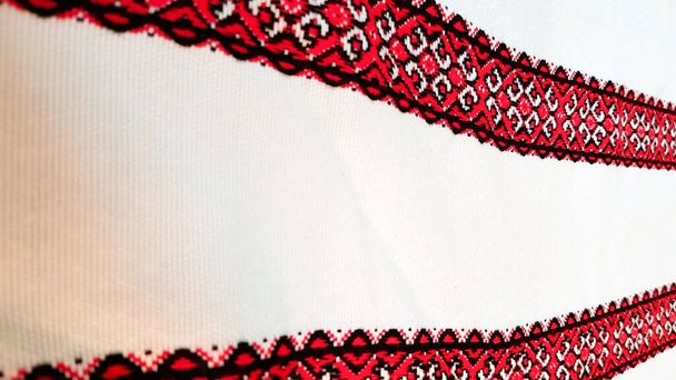 Bordado artesanal ucraniano. Adorno bordado con hilos rojo-negros sobre tela blanca. Adorno bordado en hilo negro y rojo. Bordado popular ucraniano étnico en tela blanca
. - Foto, imagen