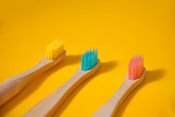 Οικολογικό μπαμπού παιδί πολύχρωμες οδοντόβουρτσες στο κίτρινο φόντο. - Φωτογραφία, εικόνα