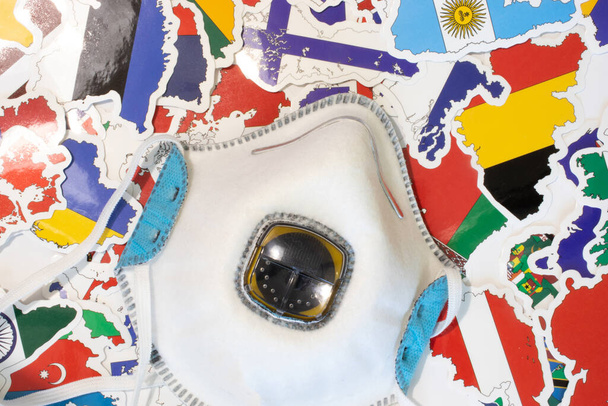 Worldwide healthcare problem concept. Medical respirator top view on country flags. Protective face mask as a sign of protection from infection or disease. - Photo, Image